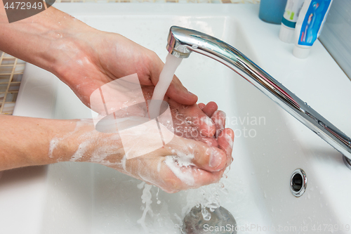 Image of A man washes his hands from the thick suds