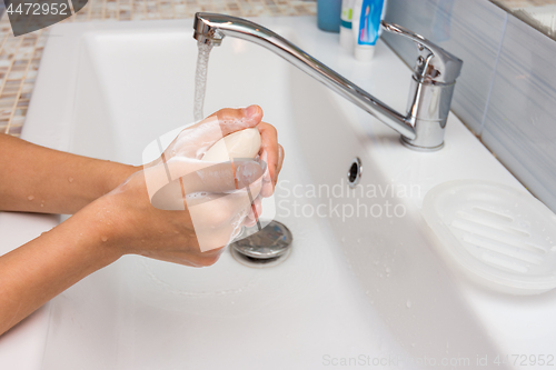 Image of The child carefully soaps his hands with soap