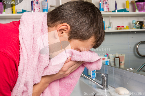 Image of Man wipes his face with a towel in the bathroom