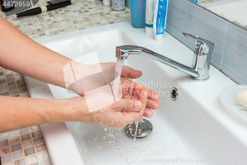 Image of A man washes the wound under the tap