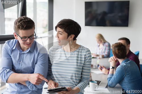 Image of Two Business People Working With Tablet in office