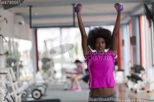 Image of woman working out in a crossfit gym with dumbbells