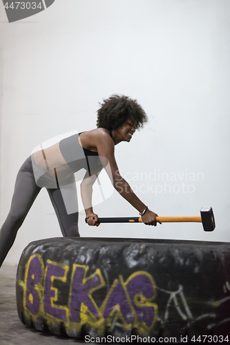 Image of black woman workout with hammer and tractor tire