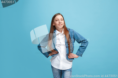 Image of The happy teen girl standing and smiling against blue background.