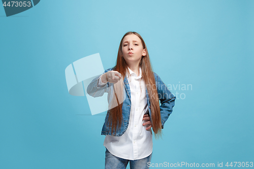 Image of The happy teen girl pointing to you, half length closeup portrait on blue background.