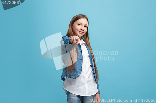 Image of The happy teen girl pointing to you, half length closeup portrait on blue background.