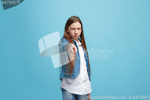 Image of The happy teen girl pointing to you, half length closeup portrait on blue background.