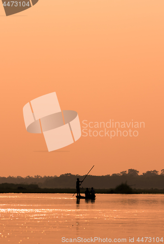 Image of Men in a boat on a river silhouette