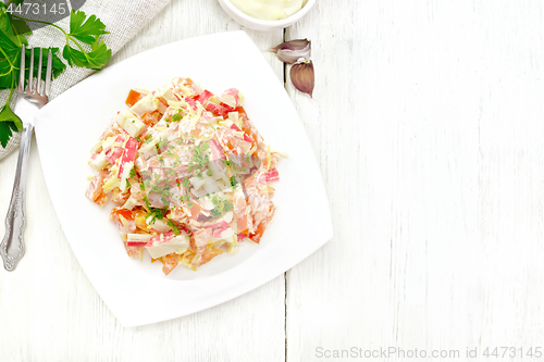 Image of Salad of surimi and tomatoes with mayonnaise on wooden board top