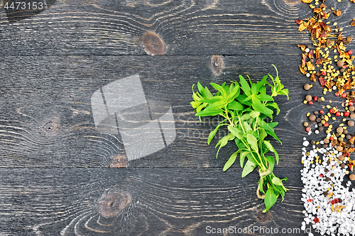 Image of Savory leaves with spices on black wooden board