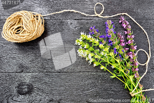 Image of Savory leaves and flowers with twine on black board