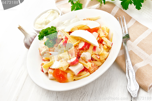 Image of Salad of surimi and tomatoes with eggs on wooden table