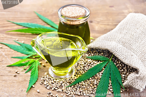 Image of Oil hemp in sauceboat and jar on old board