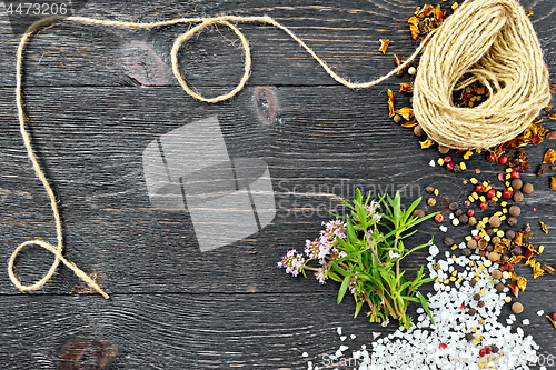 Image of Thyme leaves and flowers with twine on black wooden board