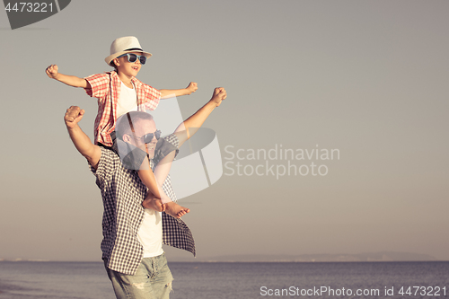 Image of Father and son playing on the beach at the day time.