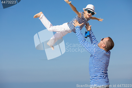 Image of Father and son playing on the beach at the day time.