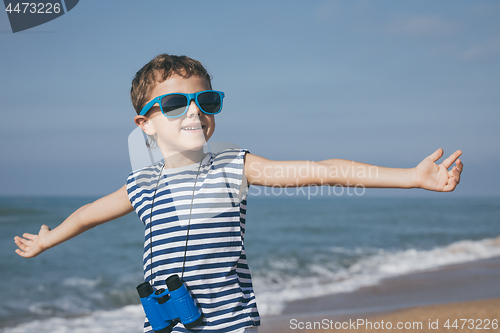 Image of One happy little boy playing on the beach at the day time.