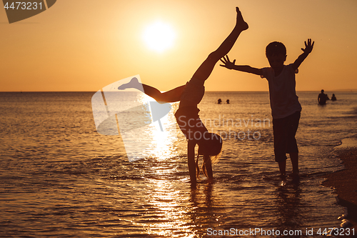 Image of Happy children playing on the beach at the sunset time.