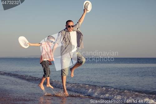 Image of Father and son playing on the beach at the day time.