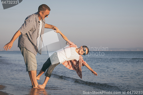 Image of Father and son playing on the beach at the day time.