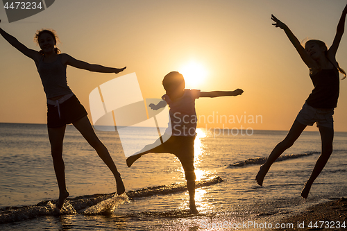 Image of Happy children playing on the beach at the sunset time.