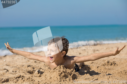 Image of One happy little boy playing on the beach at the day time.