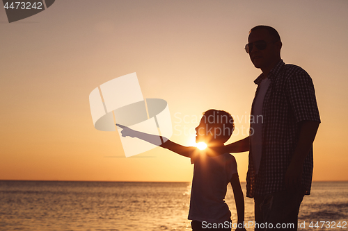 Image of Father and son playing on the beach at the sunset time.