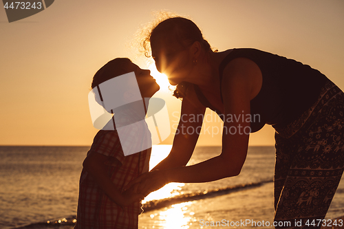 Image of Mother and son playing on the beach at the sunset time.