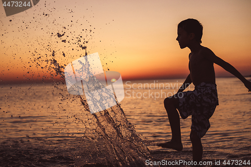Image of One happy little boy playing on the beach at the sunset time.