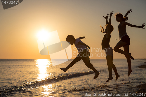 Image of Happy children playing on the beach at the sunset time.