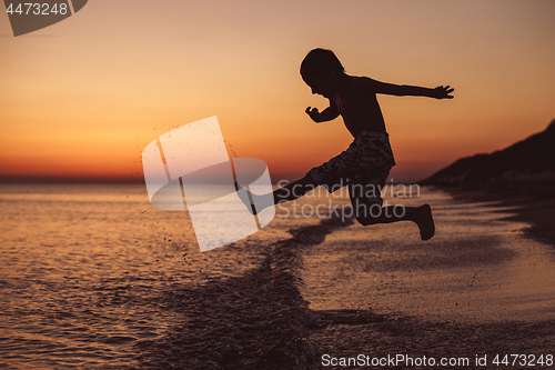 Image of One happy little boy playing on the beach at the sunset time. 