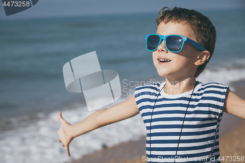 Image of One happy little boy playing on the beach at the day time.