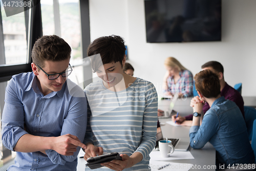 Image of Two Business People Working With Tablet in office