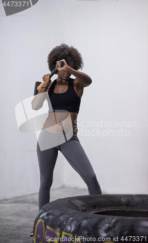 Image of black woman workout with hammer and tractor tire