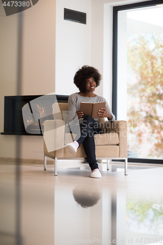 Image of black woman at home reading book