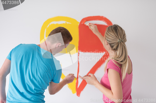 Image of couple are painting a heart on the wall