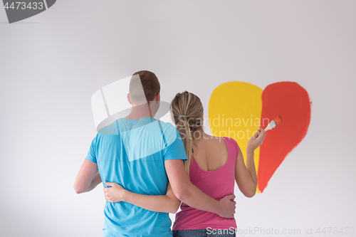 Image of couple are painting a heart on the wall