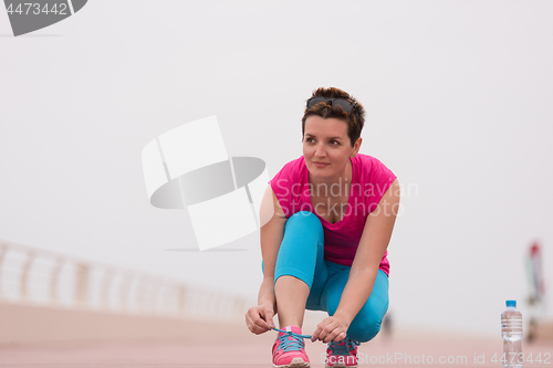 Image of Young woman tying shoelaces on sneakers