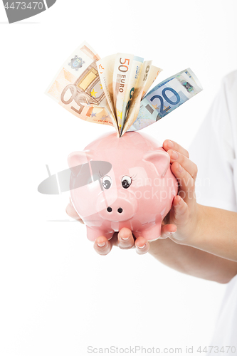 Image of A woman shows a piggy bank full of European banknotes