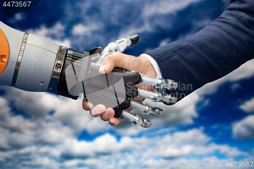 Image of Hand of a businessman shaking hands with a Android robot.