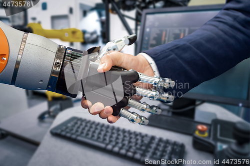 Image of Hand of a businessman shaking hands with a Android robot.