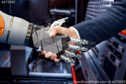 Image of Hand of a businessman shaking hands with a Android robot.