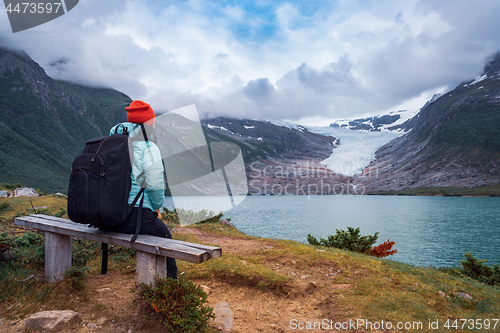 Image of Girl tourist looks at a glacier. Svartisen Glacier in Norway.