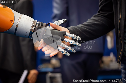 Image of Hand of a businessman shaking hands with a Android robot.