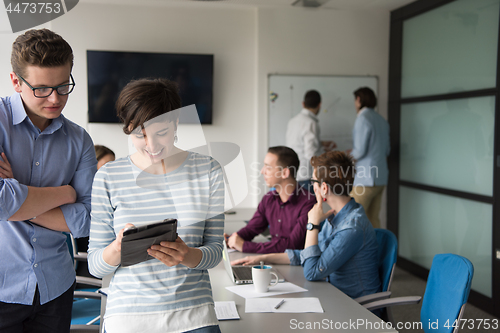 Image of Two Business People Working With Tablet in office