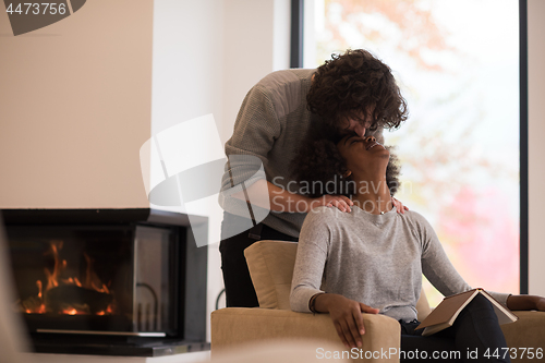 Image of multiethnic couple hugging in front of fireplace