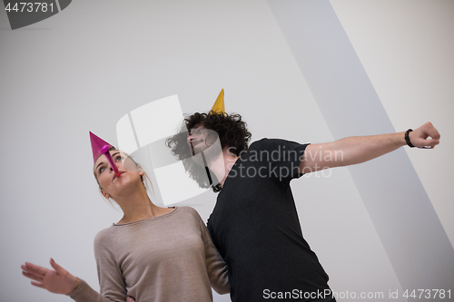 Image of couple in party hats blowing in whistle