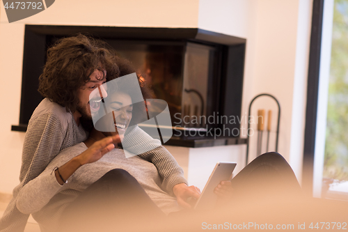 Image of multiethnic couple using tablet computer on the floor