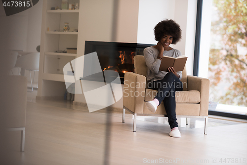 Image of black woman at home reading book