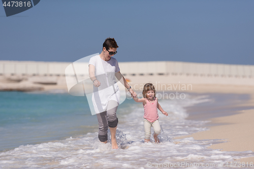 Image of mother and daughter running on the beach